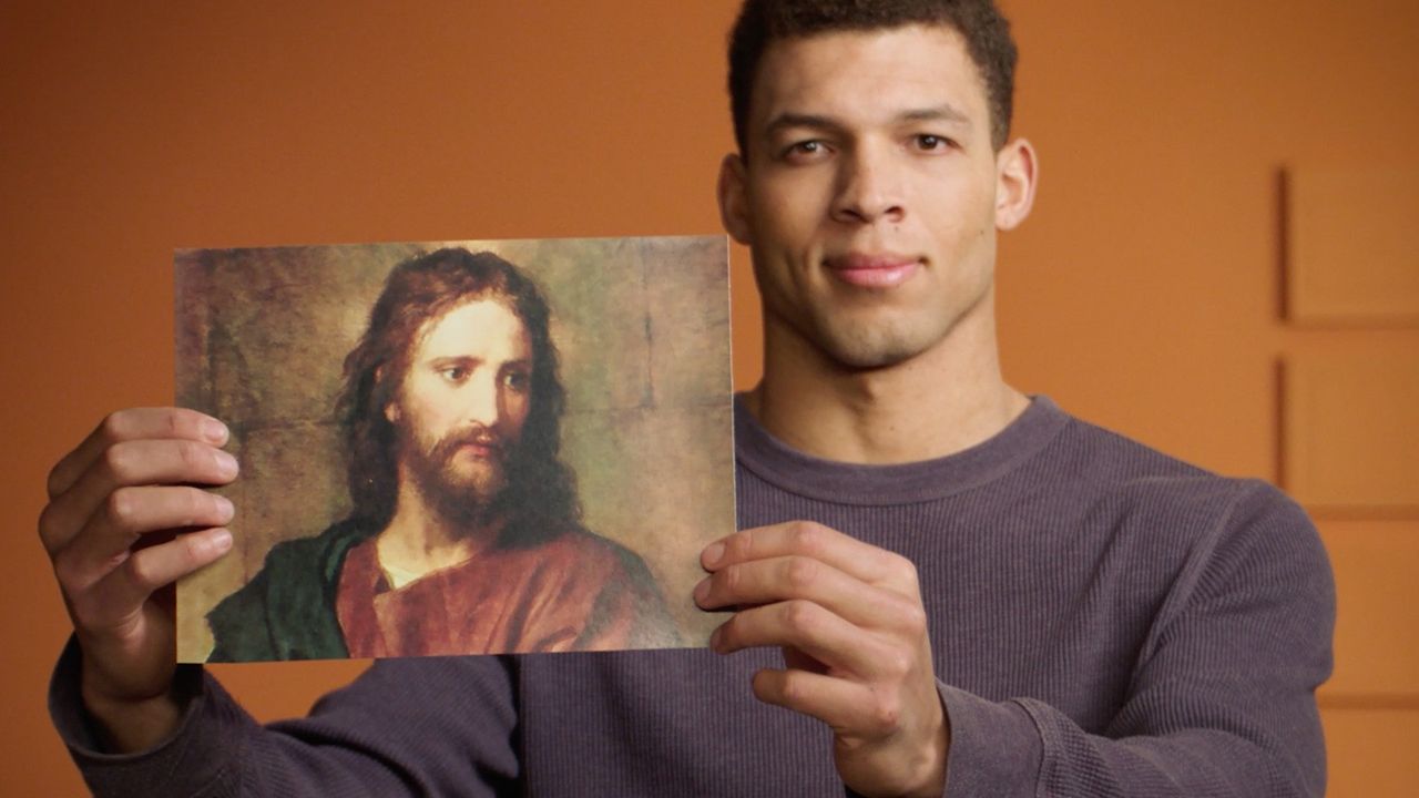 Një burrë duke ngritur lart një figurë të Jezu Krishtit