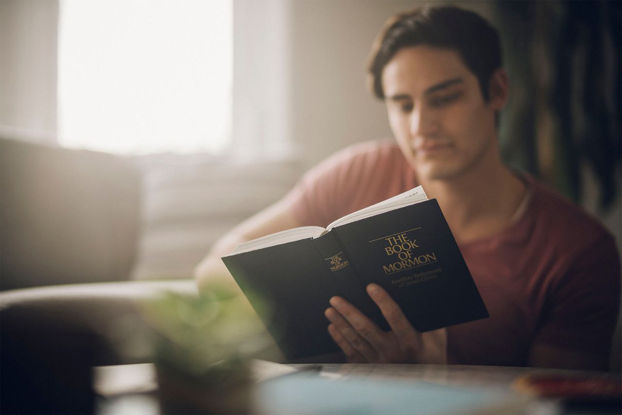 Një burrë studion Librin e Mormonit në tryezën e tij të kuzhinës
