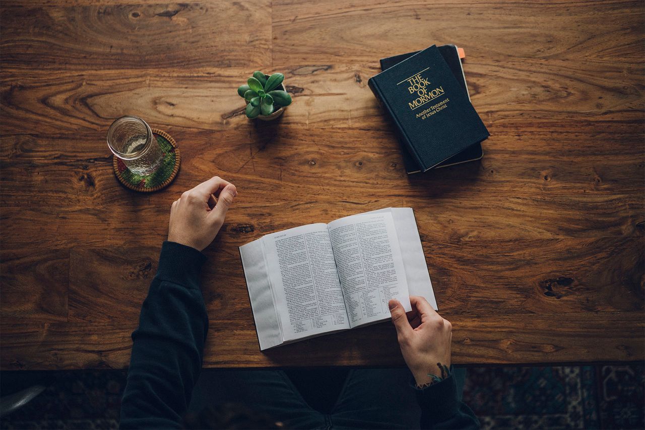 Një burrë studion Biblën dhe Librin e Mormonit në tryezën e tij të kuzhinës