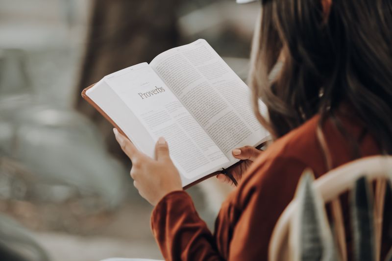 Një grua lexon librin e Fjalëve të Urta në Bibël